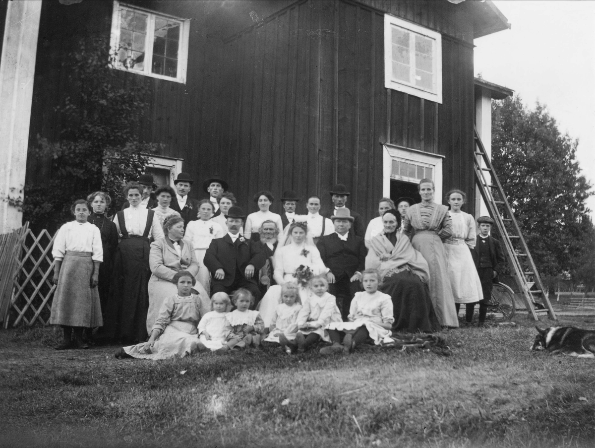 "Bröllop i Lispa". Gruppbild med brudpar sittande i mitten.
