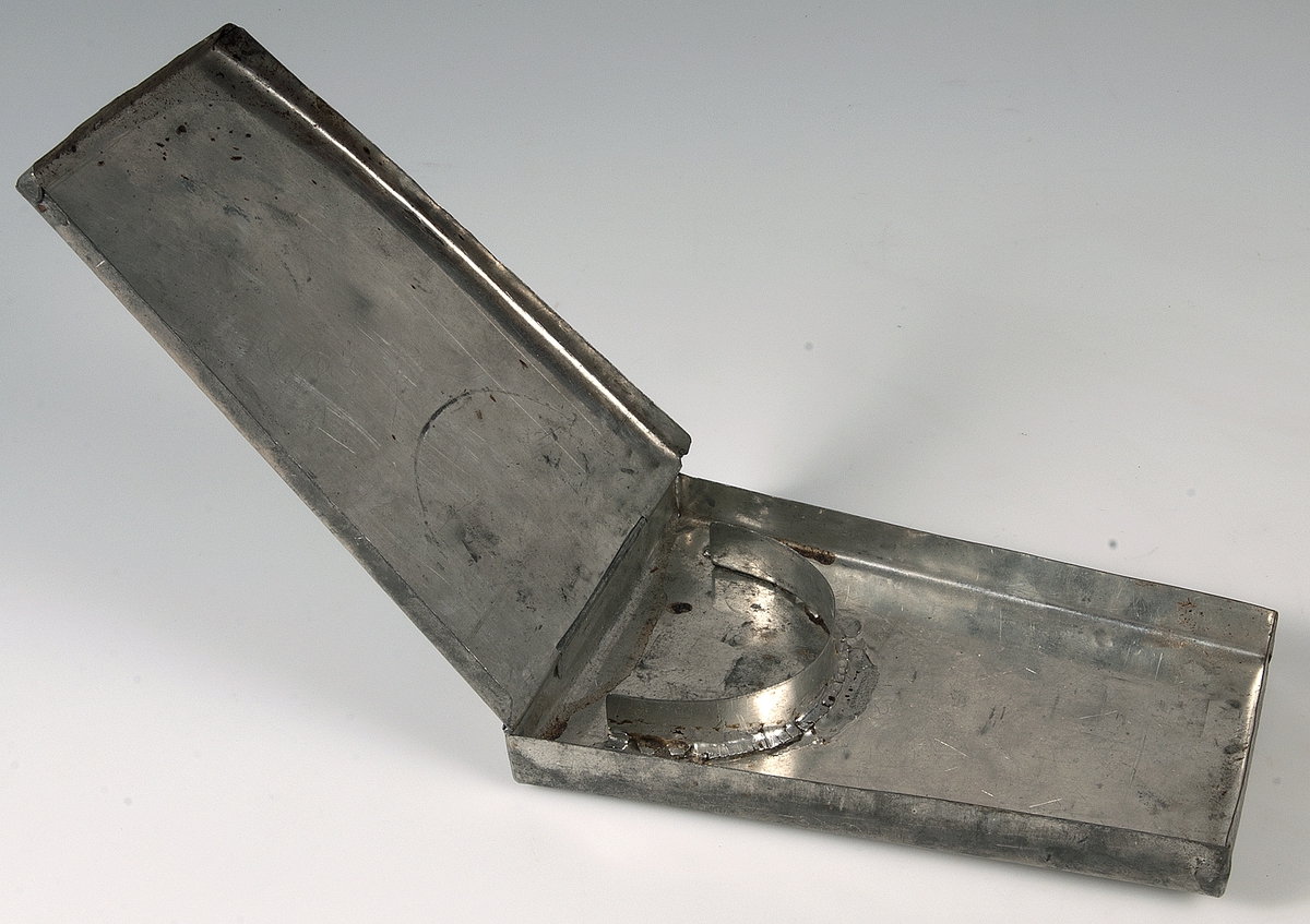 Platt plåtask, som är bredare i ena änden. Förvaringsask för kragar UM18730a.