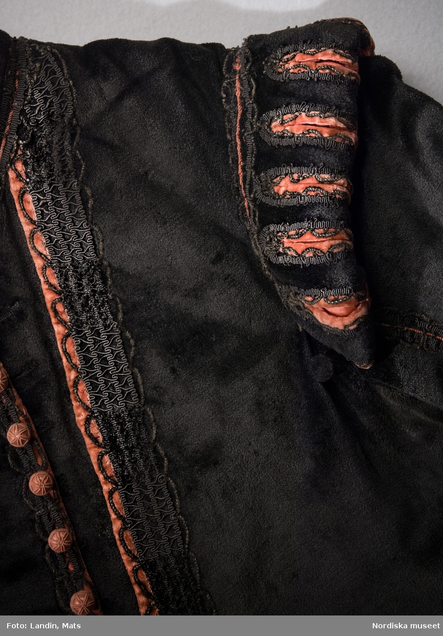 Nationella dräkten
Kungliga hovet, Stockholm, 

Sverige
 1778

Detalj av jacka av silkesammet, med dekor av gallerband och med ärmkarmar. Ståndkrage och knäppning  med 17 kulknappar i rött silke. Knapp vid vart ärmhål för att sätta fast kappan.
Sydd enligt de regler och den modell som Gustav III lanserade som nationell mansdräkt 1778.

Dräkten har tillhört överståthållaren greve Samuel af Ugglas (1750-1812).
