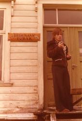 En ung mann røyker pipe foran gammel, nedlagt butikk.