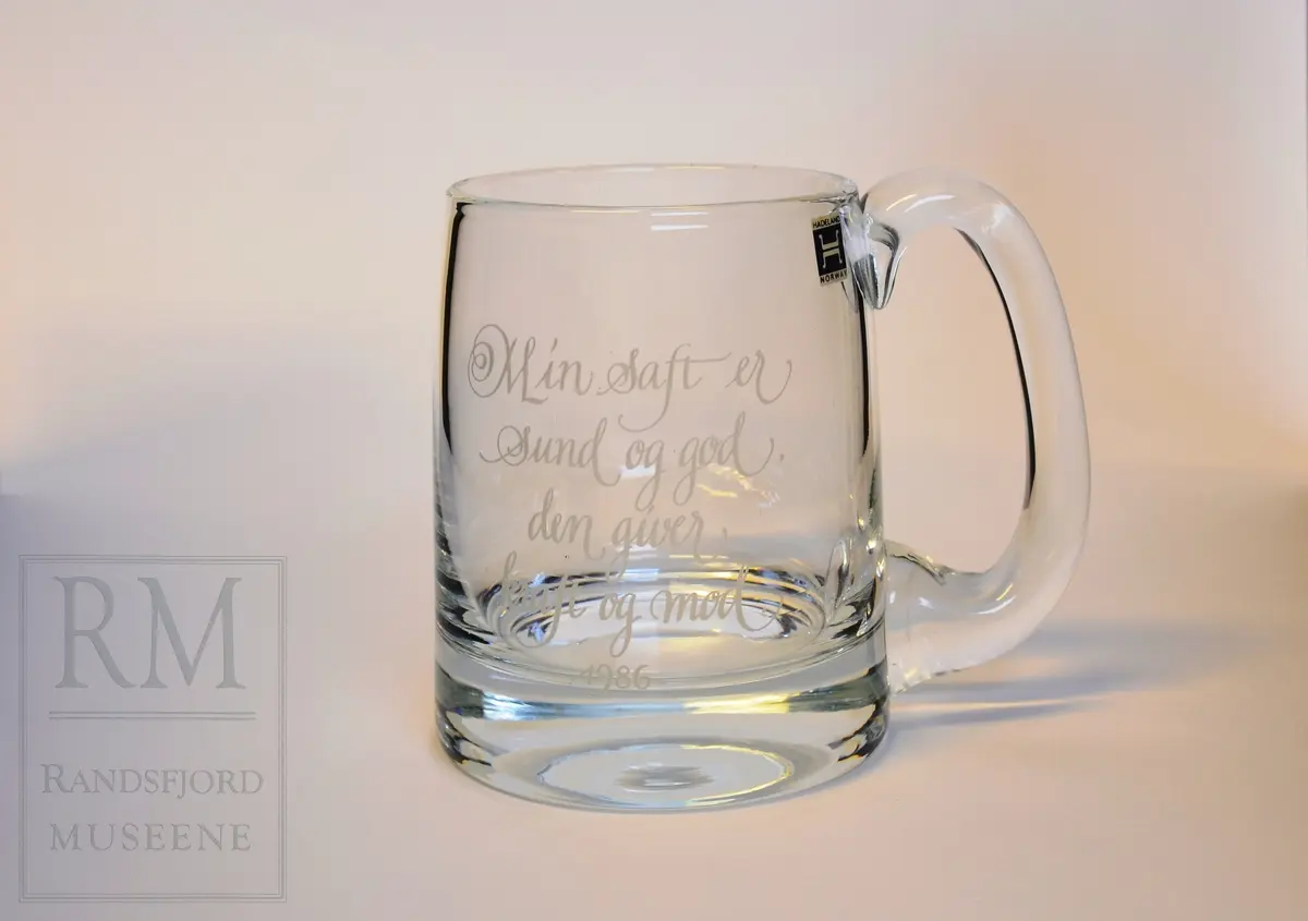 Glass med tykk bunn. Sidene skrår litt inn oppover. Kraftig hank. 