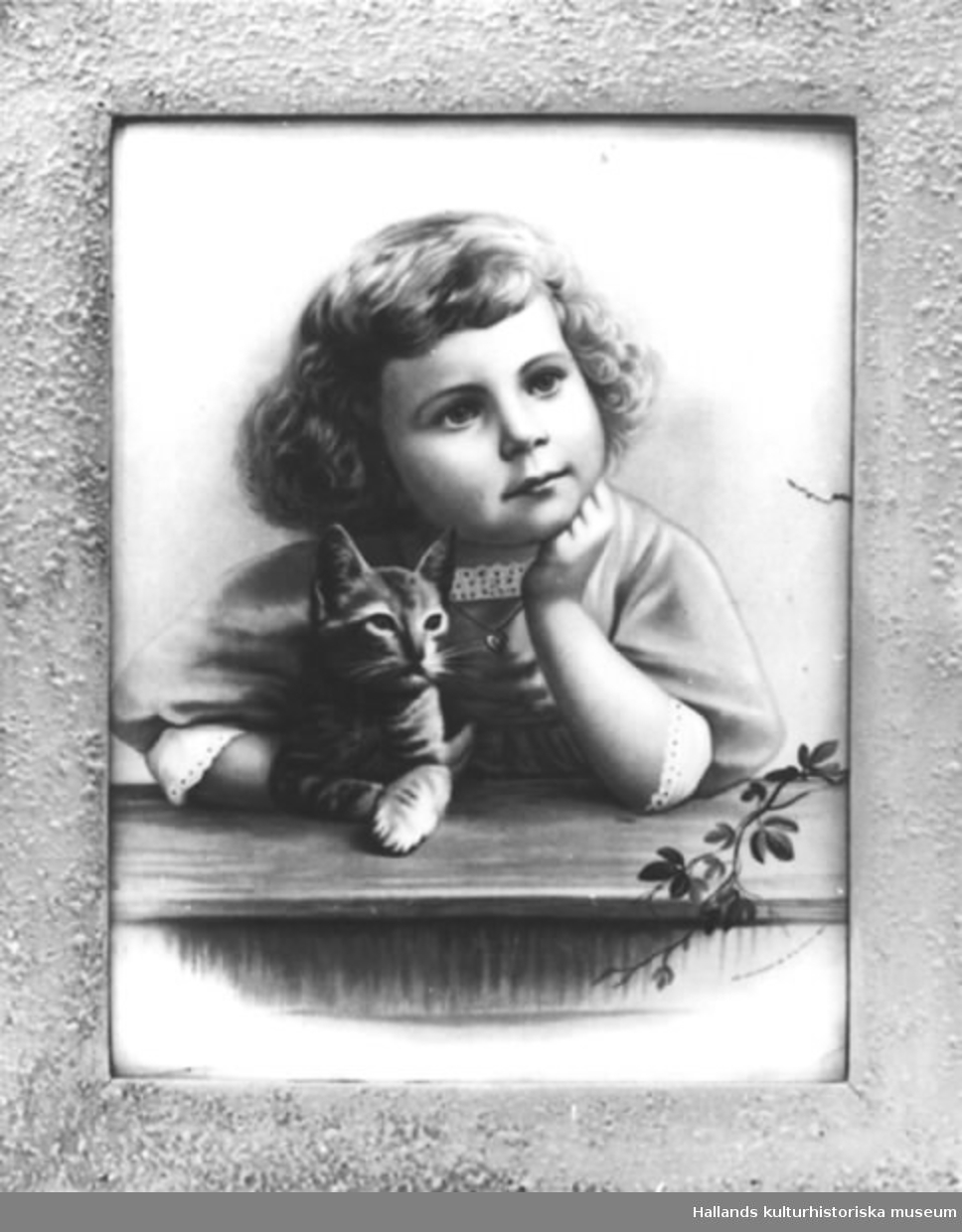 Oljetryck med ram. a) Tryck. Ung drömmande flicka med kattunge. Mått: bredd 30 cm, höjd 40 cm. b) Ram. Mått: bredd 5 cm, grå. Märkning: "FROM PHOTO. COPYRIGHT 189 BY B.J. FALK N.Y.1891".