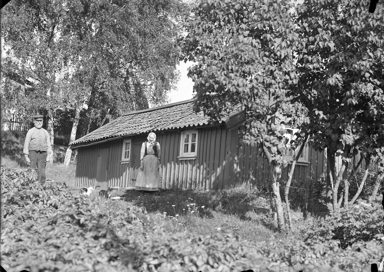 Enligt fotografens noteringar: "Tagit omkring 1924. Johan Rundqvist med syster. Gammal stuga vid sågen Munkedals Bruk."