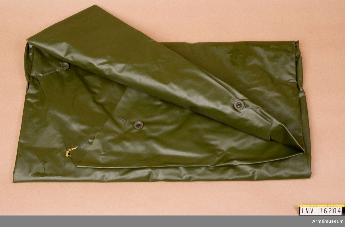 Regnskydd arbetsmodell/1967.Av olivgrön plast med hål för huvudet och med knäppanordningar för tält.