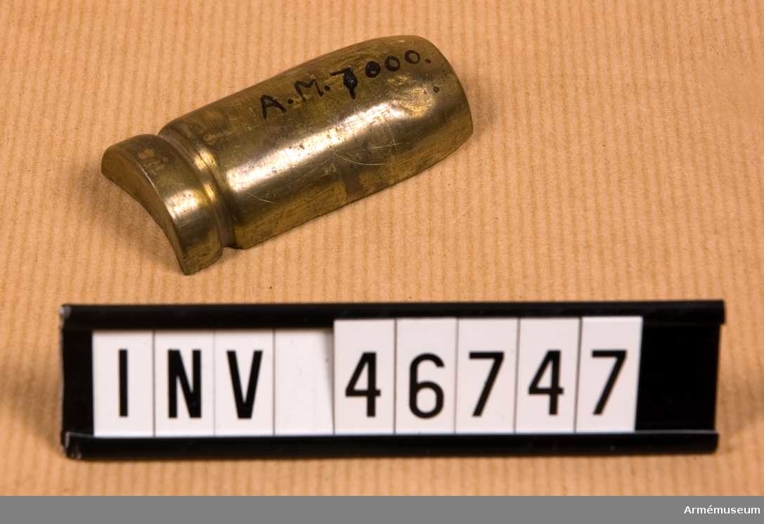 Grupp E V.
Hylsa med check, troligen av mässing som omger stålkula till Helge Palmcrantz 25,4 mm kulspruteammunition.