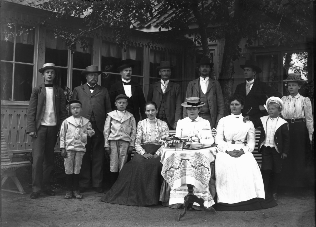 Grupp framför hus, troligen 1902