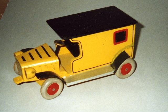 Leksaksbil form av postskåpbil, gul med svart tak,
öppenförarplats och svarta stänkskärmar. Hjulen är grå och röda.