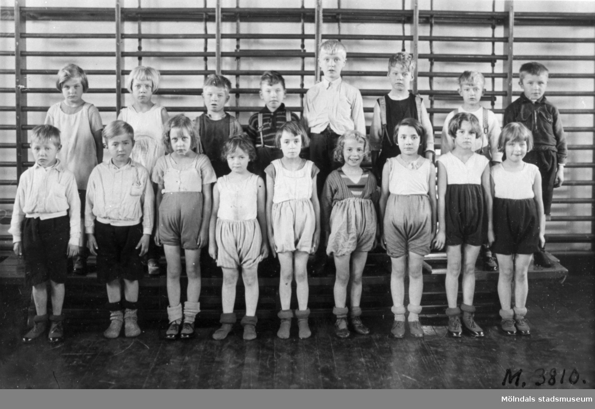 Gruppfoto av flickor och pojkar i gymnastikskläder uppställda i gymnastiksal i Toltorpskolan.