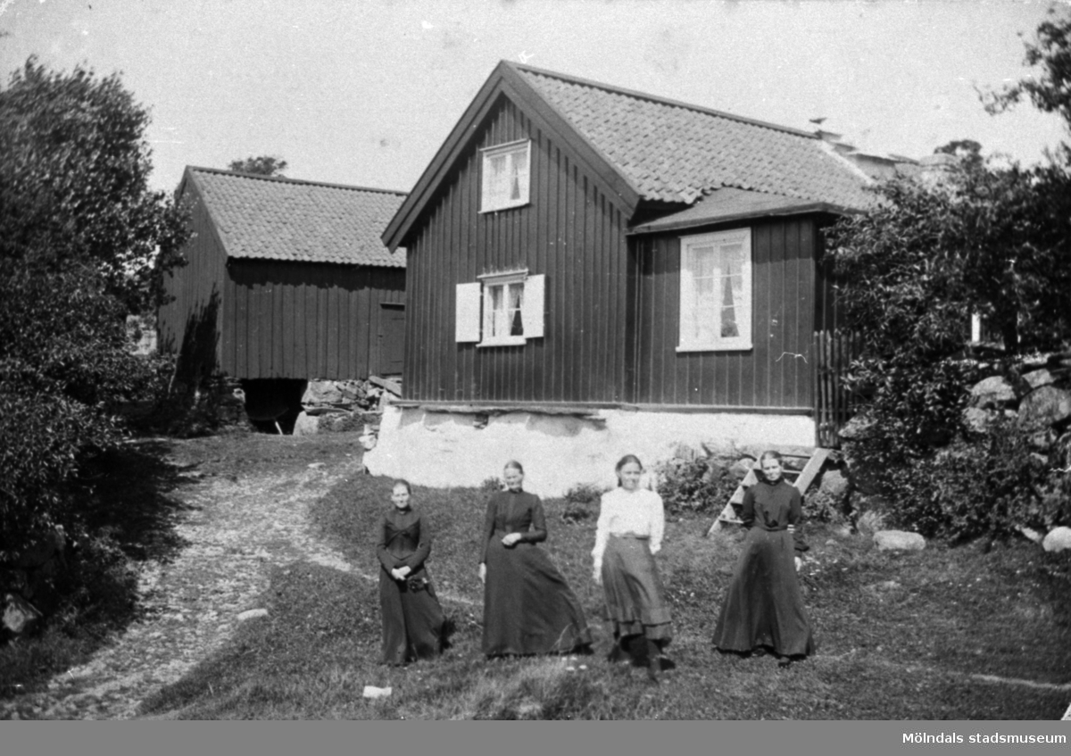 Från vänster står Anna Carlsson (1872-1955), Maria Eriksson (1840-1925), Valdeborg Johansson (1891-1970) och Josefina Eriksson (1856-1928) framför Olas stuga 1910-tal. Anna arbetade som piga i stugan.
Text på baksidan av fotot: "Ola stuga" Vommedal Östergård.
(Maria är syster till Josefina och moster till Valdeborg).