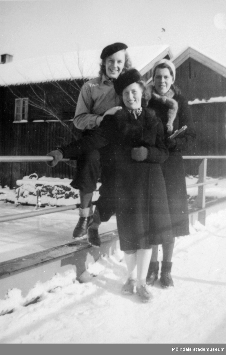 Väninnor tillsammans vid en bro i ett snöklätt Kvarnbyn. 1930-tal. Från vänster: okänd, Astrid Karlsson (gift Garthman) och Karin Karlsson. Givare är sonen Alf Garthman som arbetade många år på Mölndals stadsmuseum.