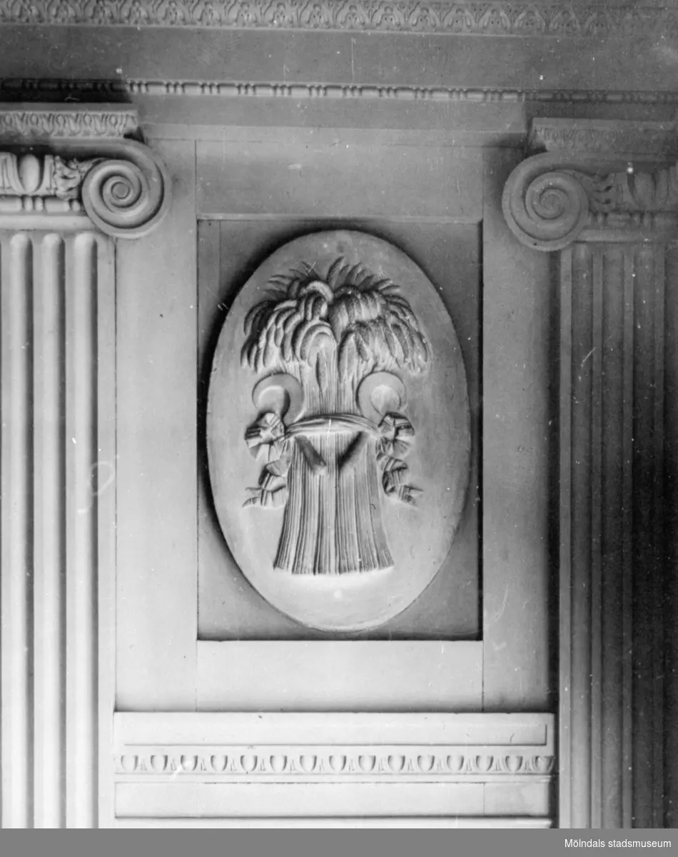 I en tablett, en stående oval relief med emblemet "vase med skära", placerad ovanför årstids-gipsfiguren "Sommaren" av Gioacchino Frulli (1766-1801). Denna sitter på sydöstra väggen i stora salongen på Gunnebo slott.
