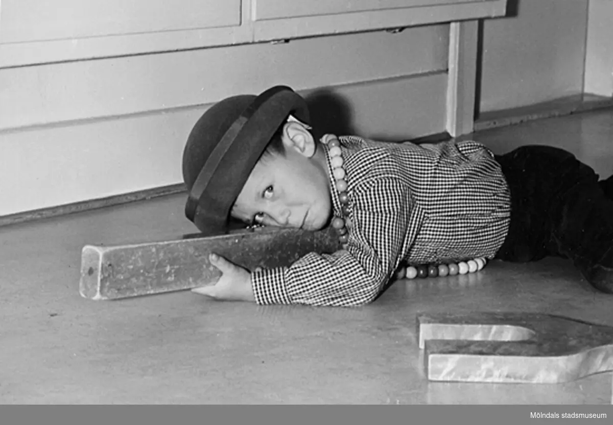 En pojke, iklädd hatt, leker med träklossar på golvet vid Holtermanska daghemmet 1953.