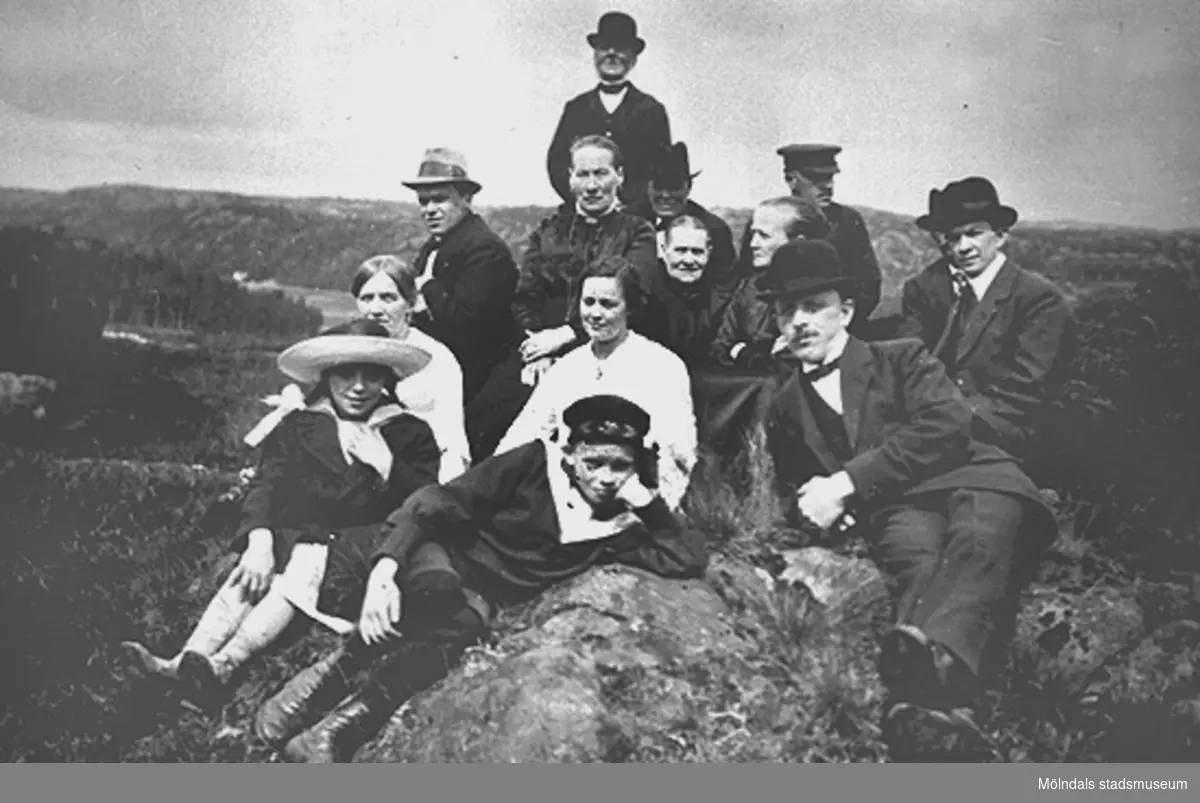 I mitten sitter Alida Eriksson, Bölet (1853 - 1928) och längst bak hennes man Johannes Eriksson (1842 - 1924). De befinner i bergen ovanför Gamla Riksvägen med Torrekulla i bakgrunden. Okänt årtal.