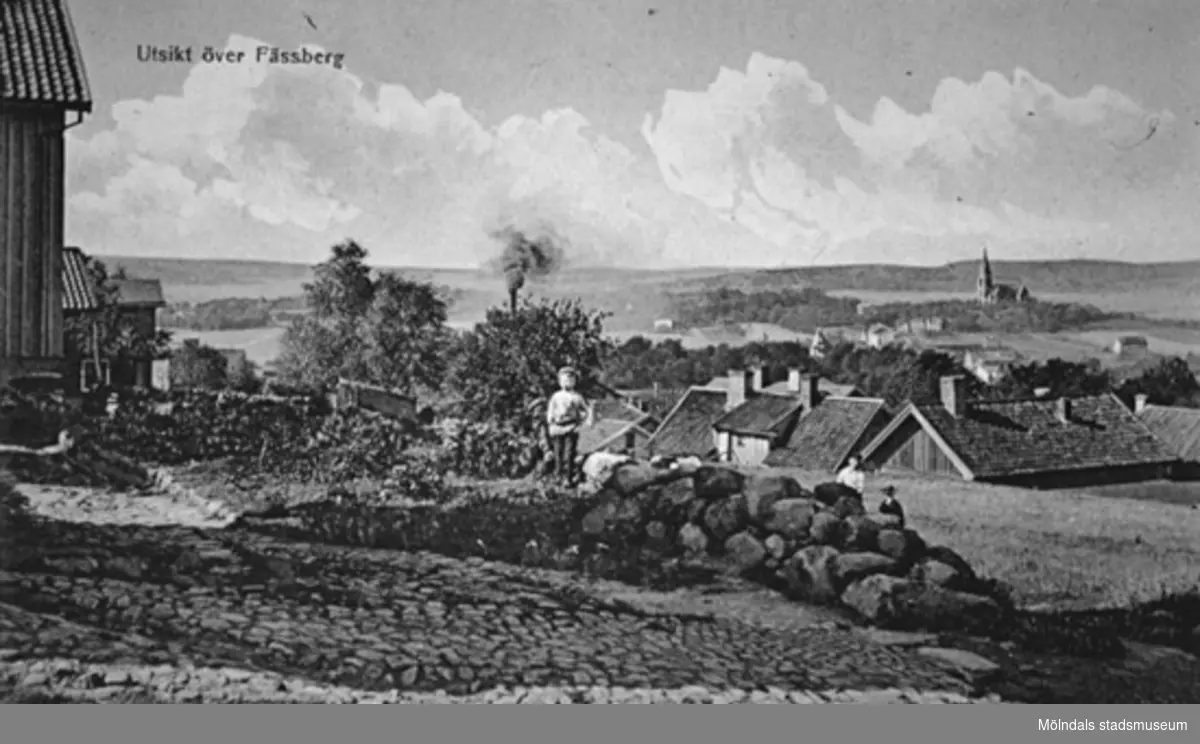 Avfotograferat vykort "Utsikt över Fässberg" taget från Görjelycksgatan med utsikt mot sydväst, 1910-tal. Man ser Roten K 8, 14, 27, 13 och 9. Pojken heter Einar Wall. I bakgrunden till höger ses Fässbergs kyrka.