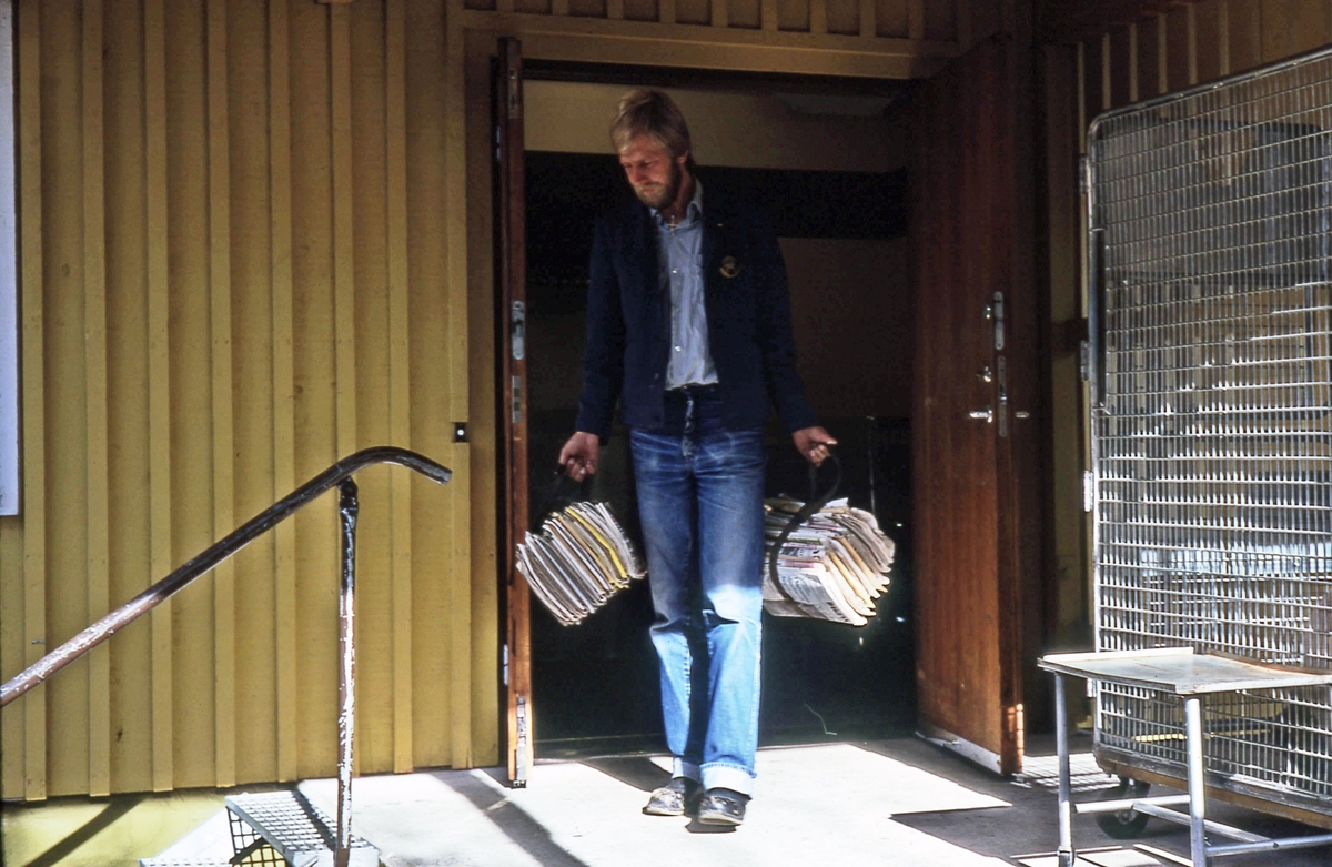Mikael Mattsson på väg ut genom dörren med buntar av post i händerna, brevbärarexpeditionen Olsborgsvägen i Vallentuna.