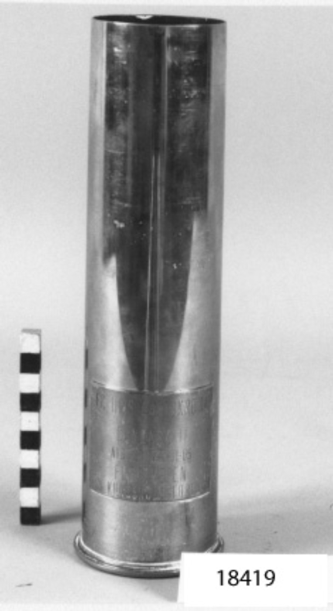 Ammunitionshylsa av mässing, cylinderformad, avskuren på mitten och förändrad till minnesföremål.
