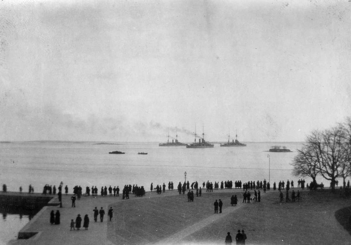 Folksamling bevittnar skepp som går förbi utanför Karlskronas hamn.
