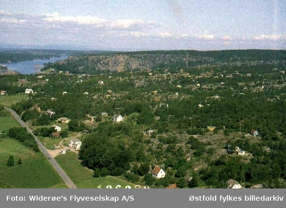 Flyfoto som viser Vestre Slevik i Onsøy, med hytteområdet Skjellumfjellet til høyre og  Hankøsundet og  fjellet Onsøyknipen i bakgrunnen., 1964.
