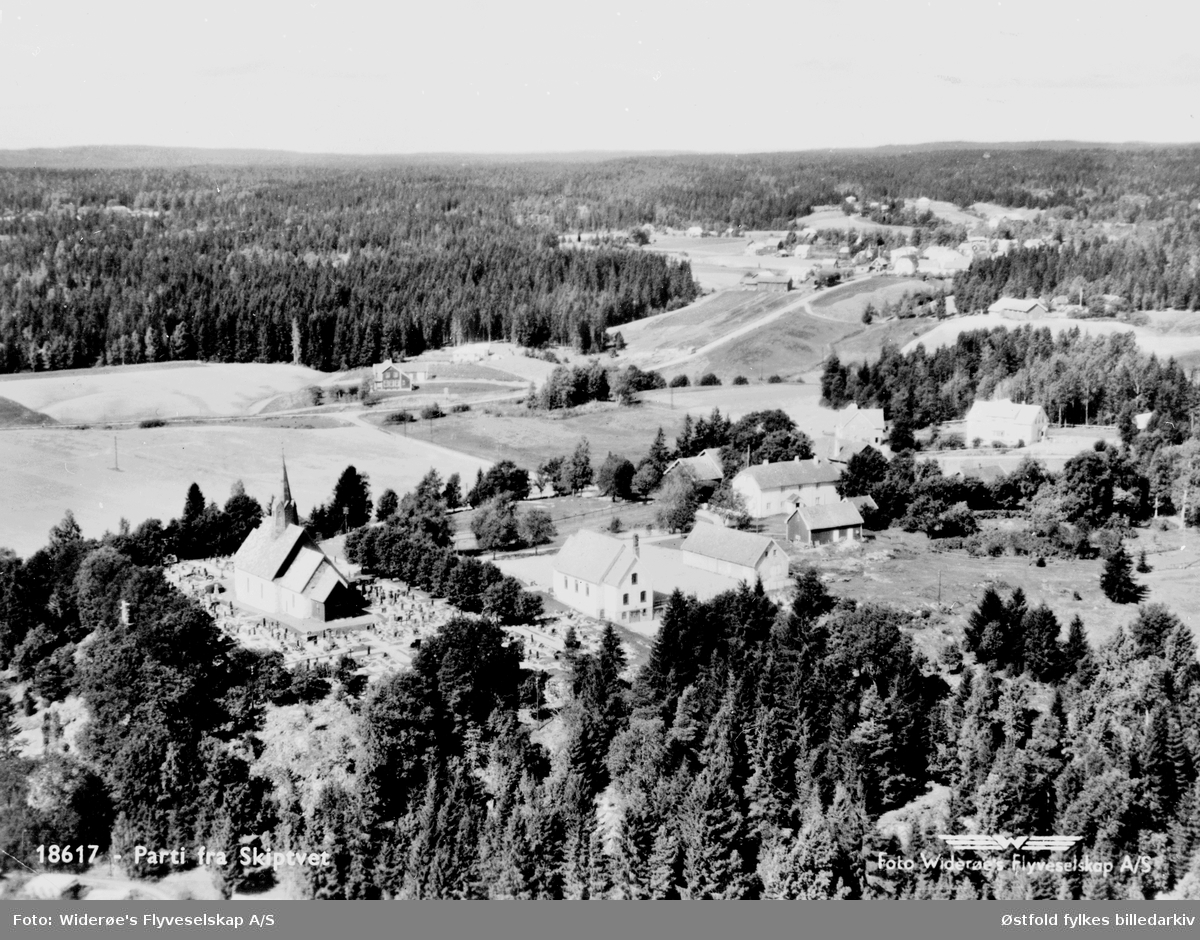 Flyfoto av Skiptvet kirke med  misjonshus, skole, legebolig, Meieribyen og området rundt  ca. 1947.
