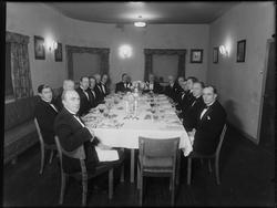 Ukjent gruppe festkledde menn rundt dekket bord, ant Sarpsbo