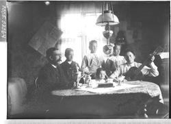 Gruppebilde av kvinne, mann og fire barn rundt et bord.