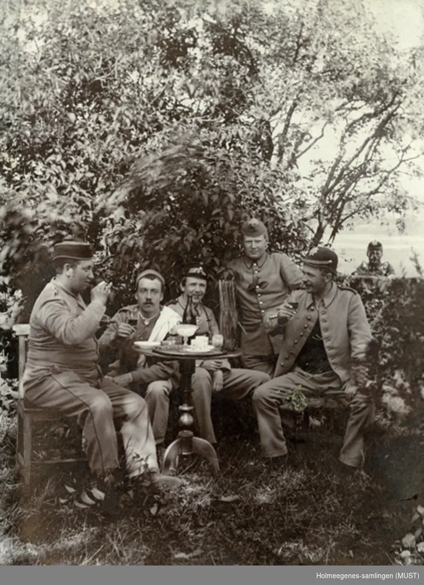 En gruppe menn i militæruniformer rundt et bord utendørs. "Kaffeslabberas".