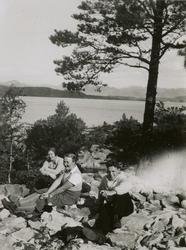 To kvinner og en mann holder matrast i ei steinur.