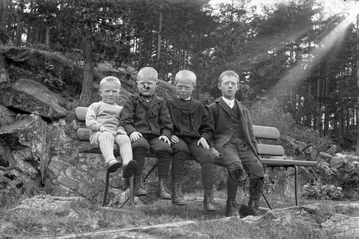 Francis, Thorleif, Arne og Finn Nilsen sitter på en benk. Ca. 1912