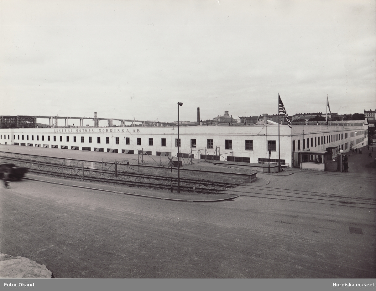 General Motors Nordiska Ab. "Troligen från samma tillfälle som NMA.0074669. GM Nordiska fotograferat från Hammarby Allé. I bakgrunden syns nya Skanstullsbron under byggnad. Bron blev färdig 1946."