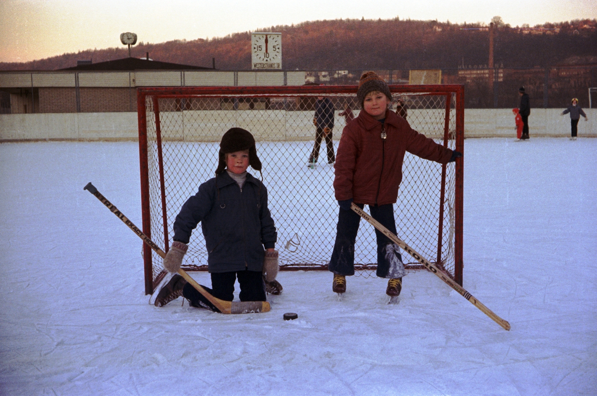 På Vapenvallen i Huskvarna är skridskobanan frusen och två pojkar spelar ishockey. Till vänster i målet är Jan Svensson (Bylund) (1).