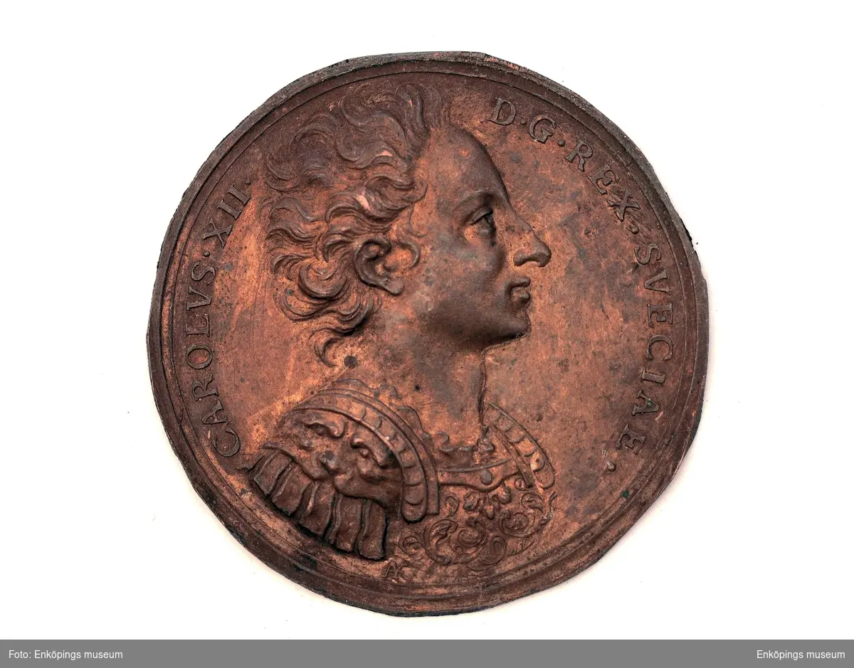 Gjuten medaljhalva av koppar. Profilbild av Karl xii med texten " CAROLUS XII D G REX SVECIAE".