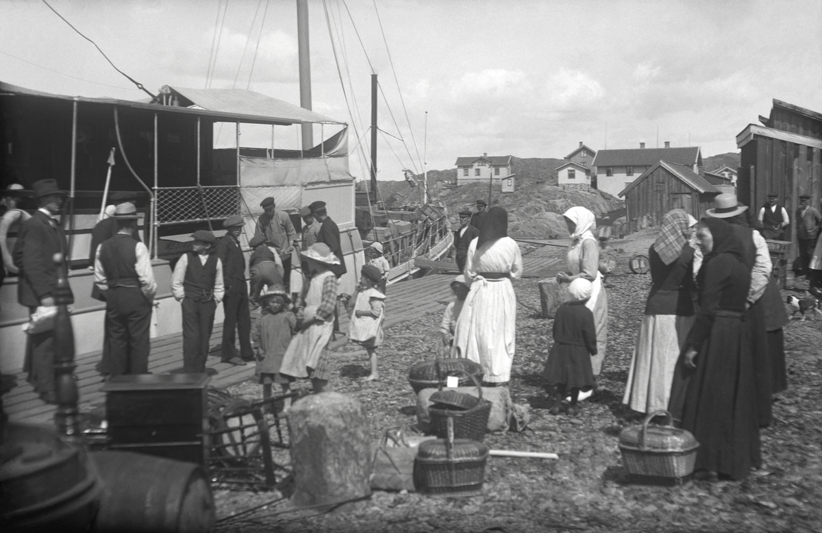 Bohuslänskt fiskeläge ungefär 1920. Passagerarna, finklädda för resan, gör sig klara att gå ombord.