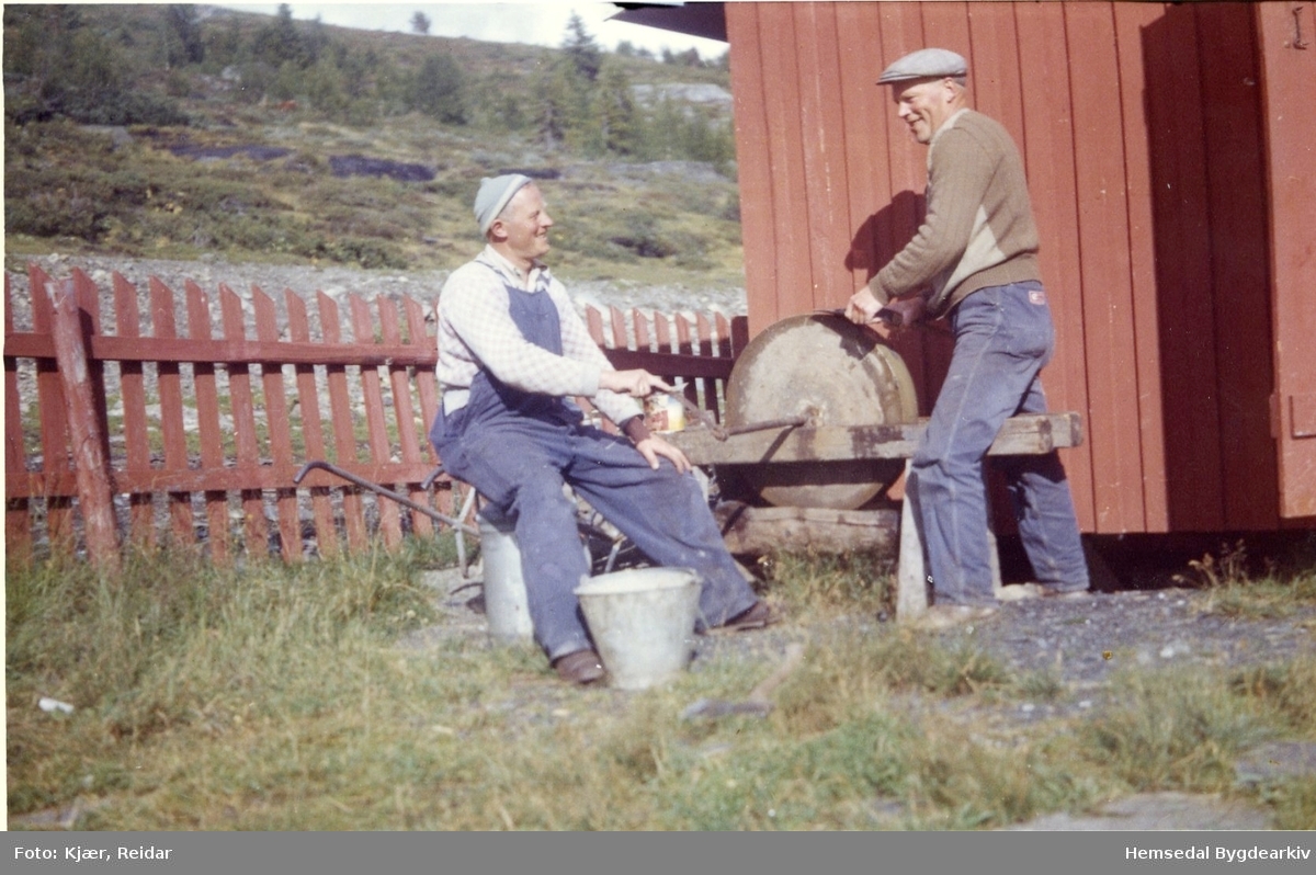 Snikkarane må ha kvass reiskap. Torleiv Veslestølen, fødd 1916, dreg slipesteinen og Thomas Bjerkheim, fødd 1916, sliper.