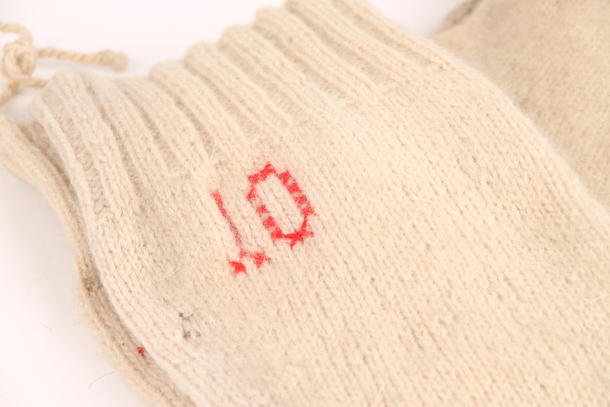 Et par gråhvite knestrømper i ull uten dekor. Det er sydd inn "r o" (?) med rødt garn under strømpekanten.