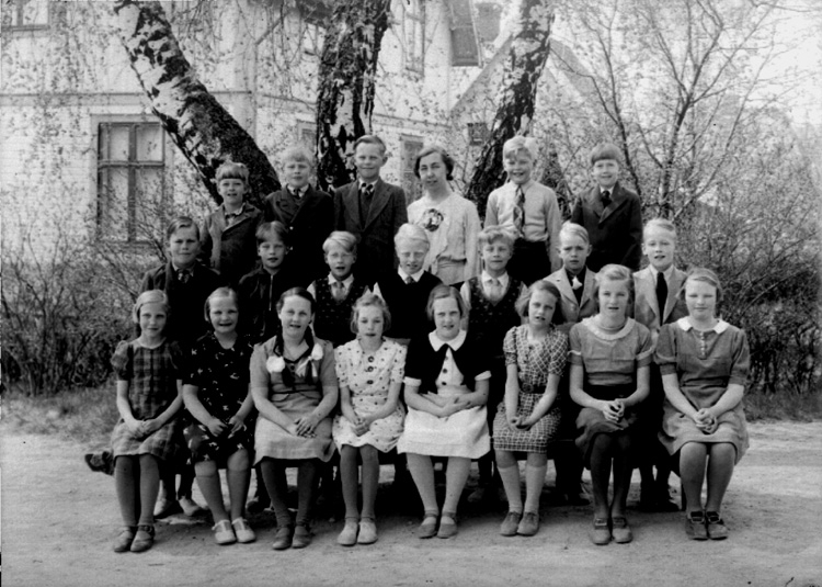 Rynninge skola, 8 flickor, 12 pojkar och lärarinna fru Eva Dahlen på skolgården.
Skolbyggnad i bakgrunden.