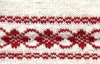 Kortärmad Barntröja stickad i omerceriserad bomullsgarn 8/4 , 
Mönsterbården Blomrankan i rött nertill och bålen på vit botten.
en virkad röd kant i halsringningen.