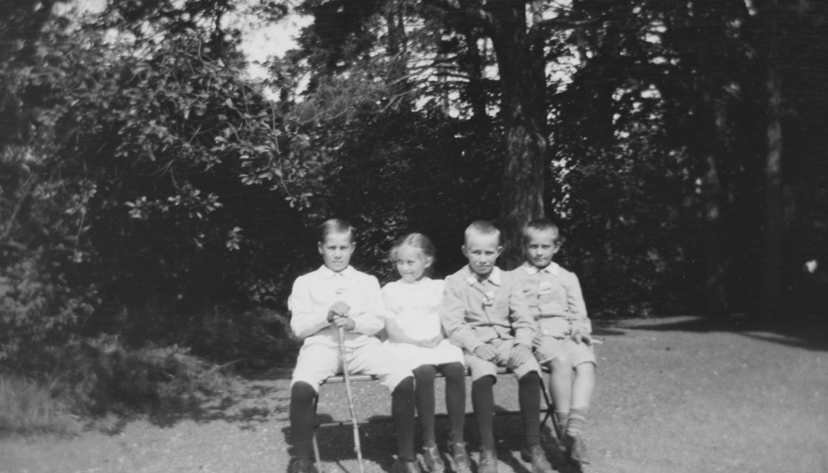 Fra venstre: Haaken Christian, Ise (Louise), Erich Monsen og Christian Pierre sitter sammen på en benk i sola.