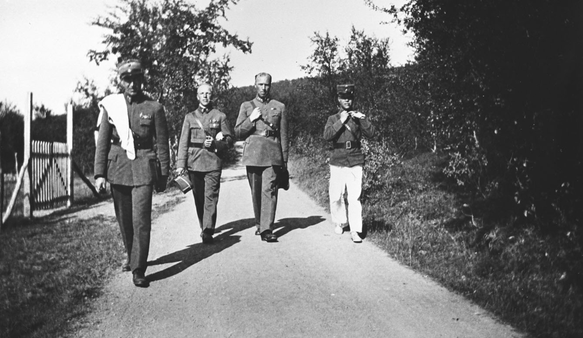 Vi antar at bildene er tatt i forbindelse med gjenopprettelse av Varanger batlajon 01.07.1934. Bildet viser fire offiserer på vei til/fra eksersersplassen på Nybergmoen 1934.