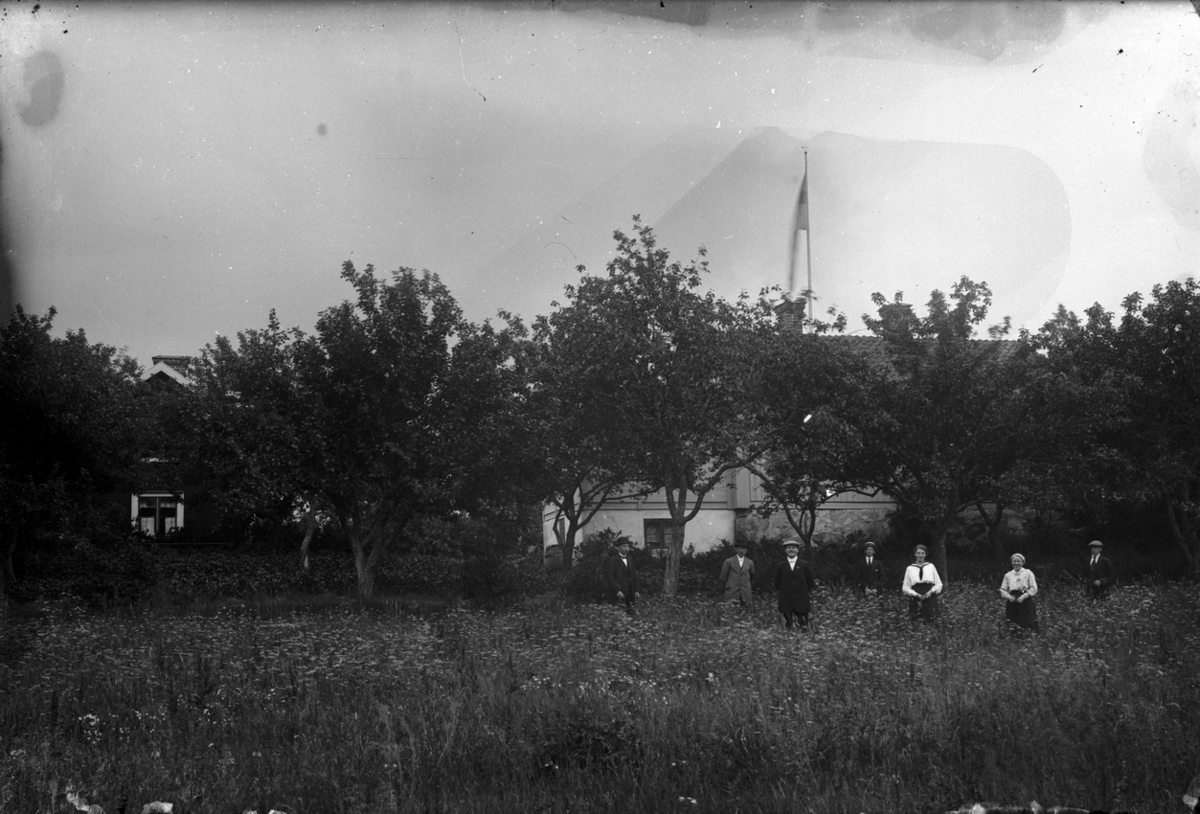 Familjegrupp sju personer i trädgården. Bostadshus i bakgrunden.
Bilden tagen i Öskevik.