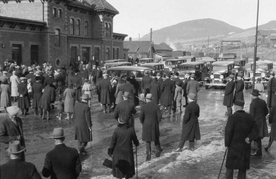 Lillehammer jernbanestasjon, mange menesker og biler  foran stasjonen, 1930-åra
