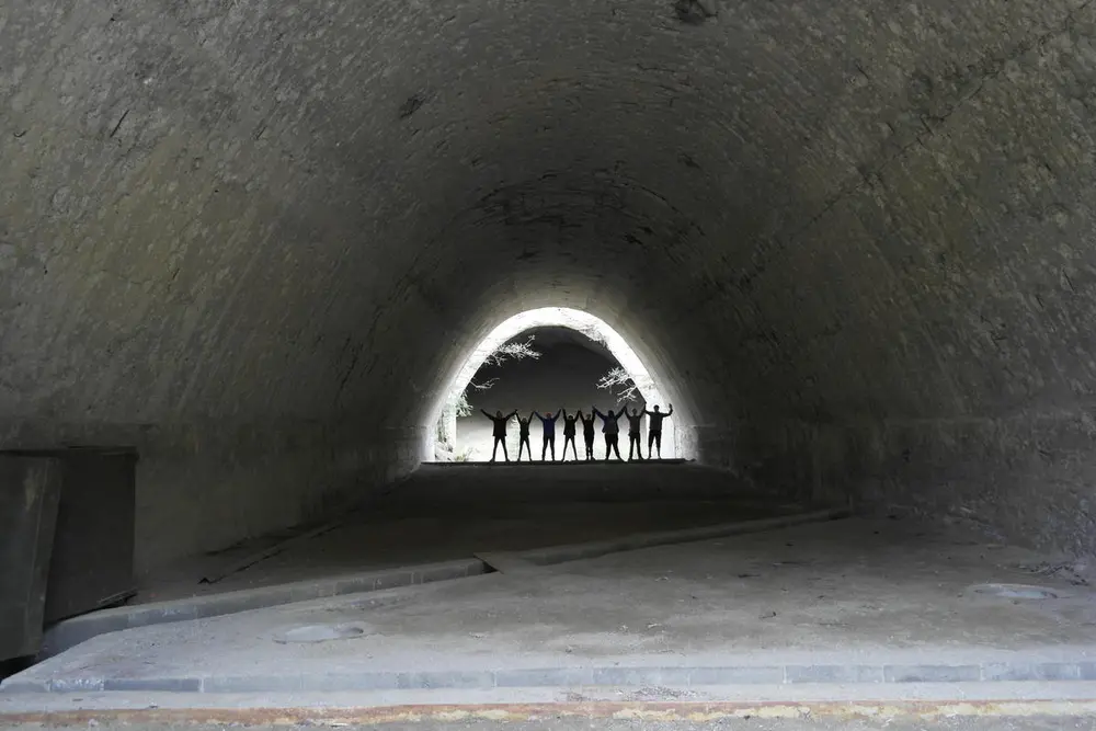 8 elever står i enden av et tunnel. De holder hverandre i hånden