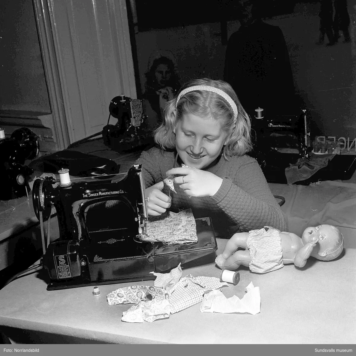 Sykurs för 24 flickor i åtta-tioårsåldern i Singers symaskinsbutik på Storgatan. I fyra dagar fick flickorna, under ledning av fröknarna Vivi Eriksson och Gurli Uhlin, lära sig att tillverka kläder till sina dockor.