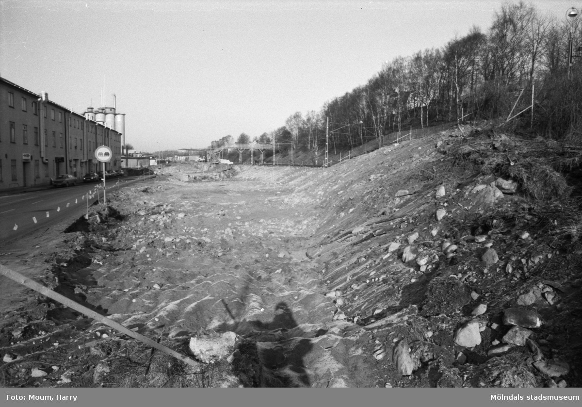 Vägarbete i "Kråkan" (Kvarnbygatan i Mölndal), år 1984. Till vänster ses byggnaden "Strumpan" (Kvarnbygatan 10-14) och bakom detta ses Soabs silotorn.

Fotografi taget av Harry Moum, HUM, Mölndals-Posten, vecka 12, år 1984.