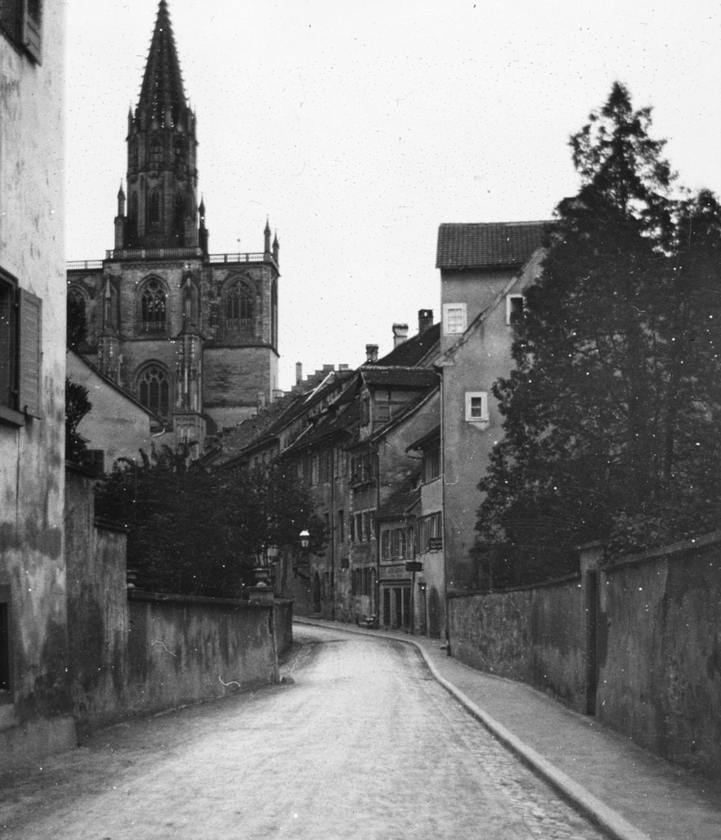 Skioptikonbild med motiv från Konstanz. Gata med katedralen Konstanzer Münster i bakgrunden.
Bilden har förvarats i kartong märkt: Konstanz. 1906