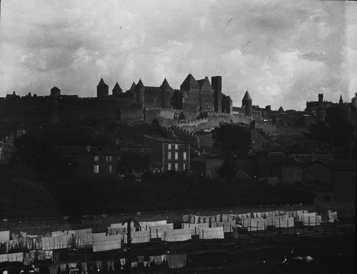 Skioptikonbild med motiv av vy över Carcassonne med medeltida borgen Cité de Carcassonne i bakgrunden.
Bilden har förvarats i kartong märkt: Höstresan 1907. Carcassonne 7. No:14.