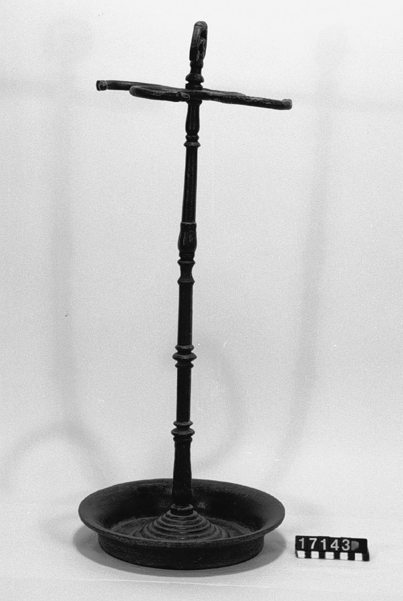 Paraplyställ av gjutjärn, med rund skål, ståndare med ornerat handtag, med fyra cirkelbågformade hållare med ormhuvuden.