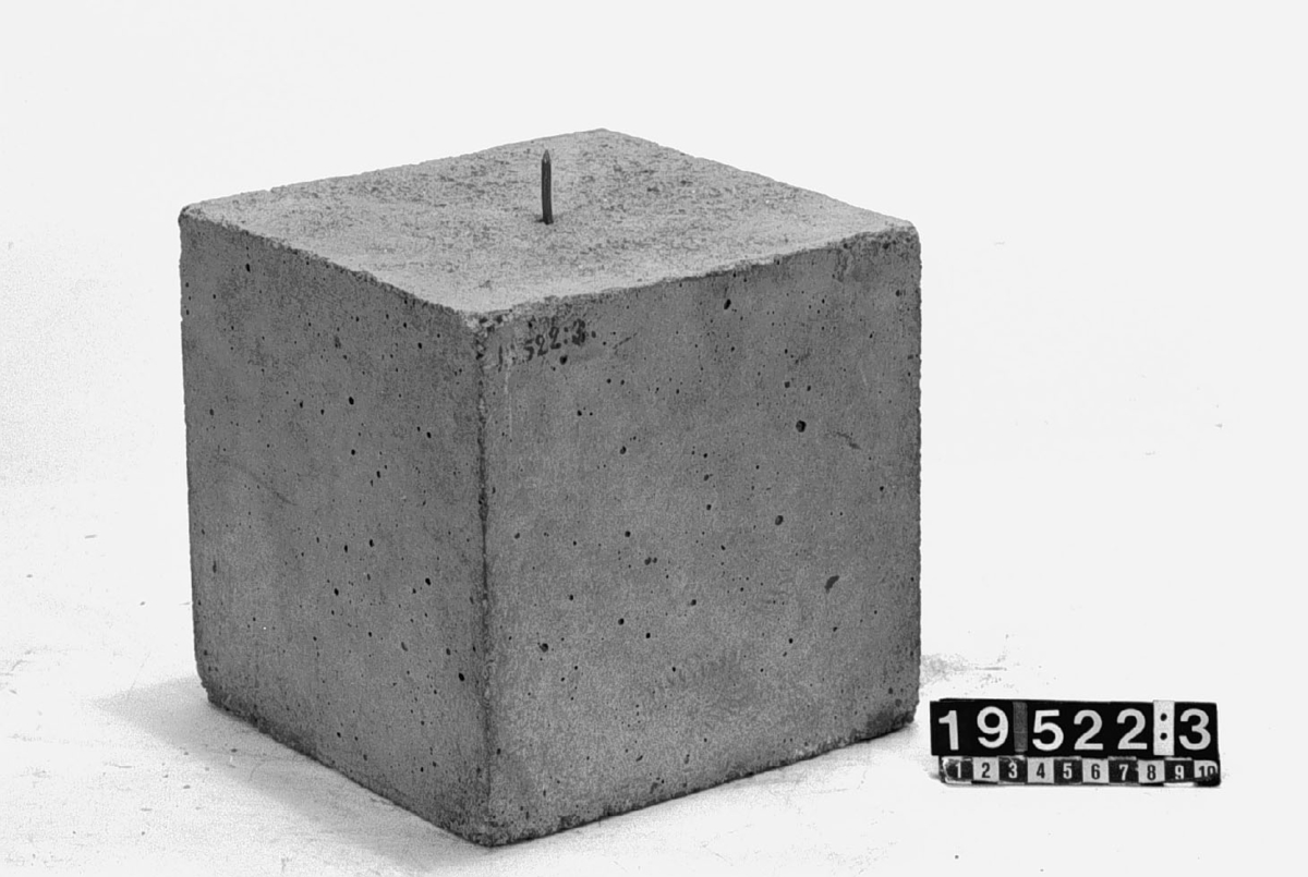 Cementkub, tål 200 tons belastning.
Tillbehör: Förevisningspil av masonit.