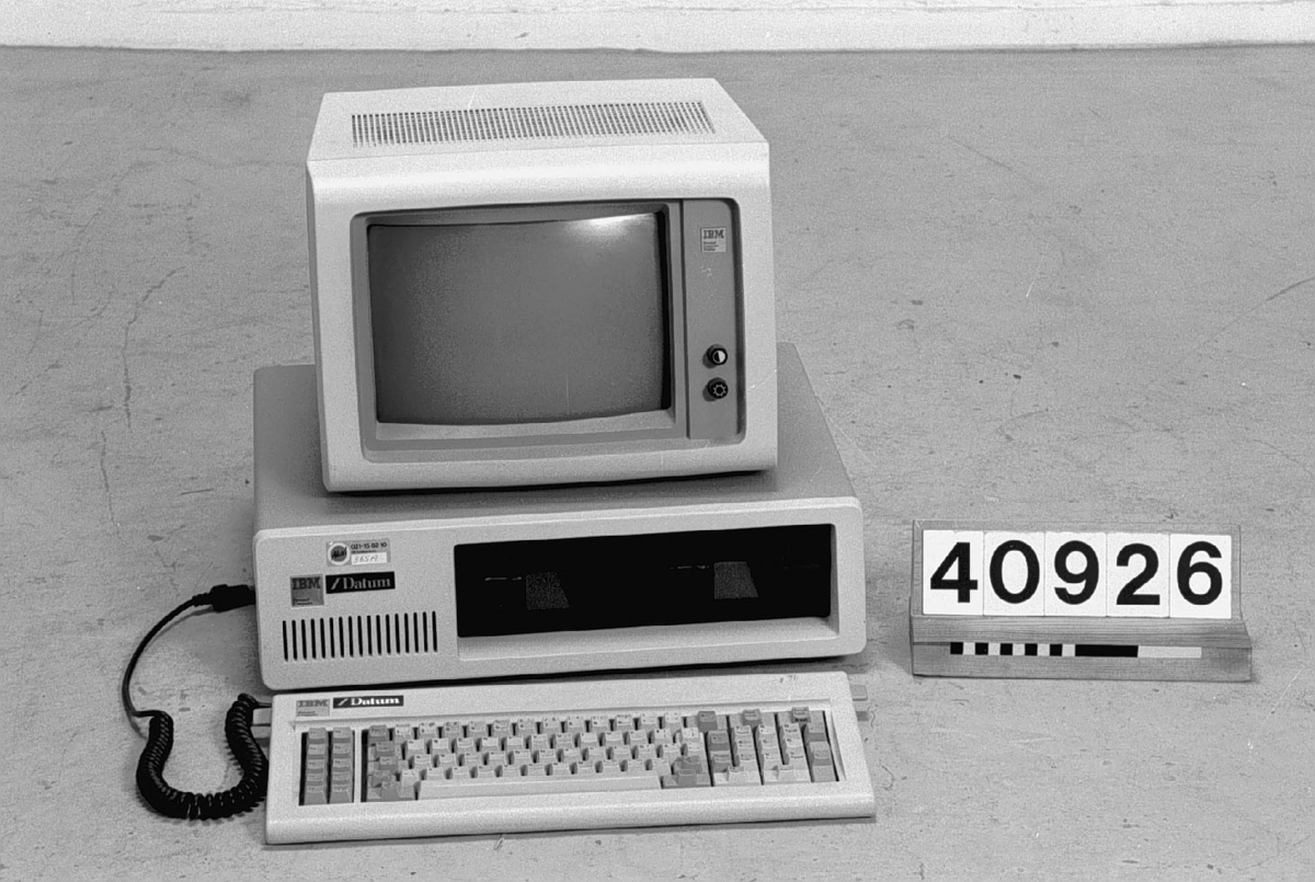 Persondator bestående av centralenhet, bildskärm och tangentbord. Centralenhet IBM 5150. Ytterhölje i grå plast. Vinklad front med indragen frontpanel i svart plast med två 5,25-tums diskettenheter, vardera rymmande 160 kB. Strömbrytare (vippomkopplare i röd plast) på höger sida. Anslutningskontakter för bl.a. nätström, tangentbord och bandspelare på baksidan. Fem expansionsplatser enligt ISA-standard varav tre är upptagna. Processor Intel 8088 med klockfrekvensen 4,77 MHz. RAM-minne på 16 kB. En BASIC-tolk från Microsoft lagrades på ROM-minnet. Skylt på framsidan: IBM Personal Computer. Skylt med återförsäljarens namn (/Datum). Tillverkad i Skottland.  IBM 5151. Monokrom bildskärm med CRT-bildrör. Ljusgrå och mörkgrå plast. Rattar för ljus och kontrast på framsidan. Skylt i metall: IBM Personal Computer Display. Nätsladd och bildskärmssladd löper ut från kanal undertill mot baksidans nederkant. Tillverkad i Taiwan.  Tangentbord av ljusgrå plast och metall. Fullängdstangentbord med 83 tangenter. 10 funktionstangenter och numerisk del. Skylt i metall: IBM Personal Computer. Skylt med återförsäljarens namn (/Datum). Tillverkad i Storbritannien.