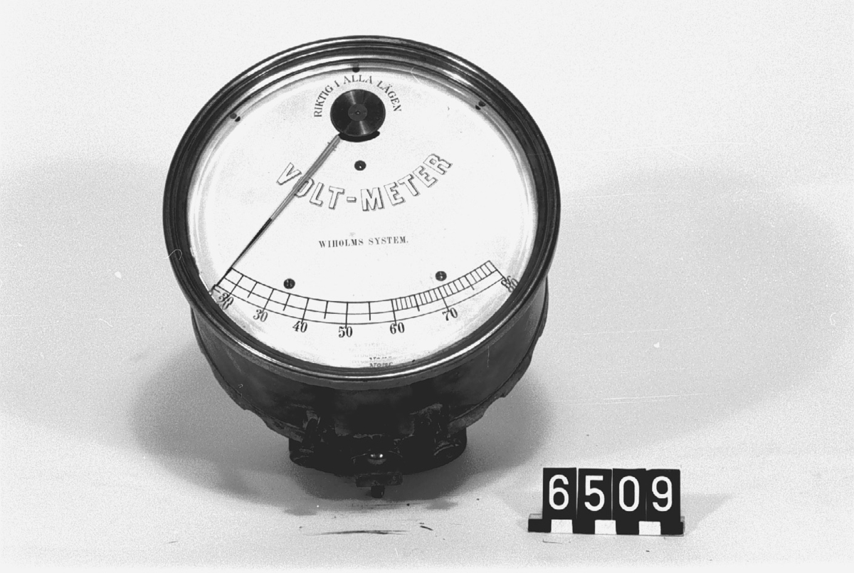 Text på visartavlan: "Riktig i alla lägen, Volt-meter Wiholms system, 0-80". Inpressat: "Aktiebol., Mekanikus, Stockholm". "N:o 186".
