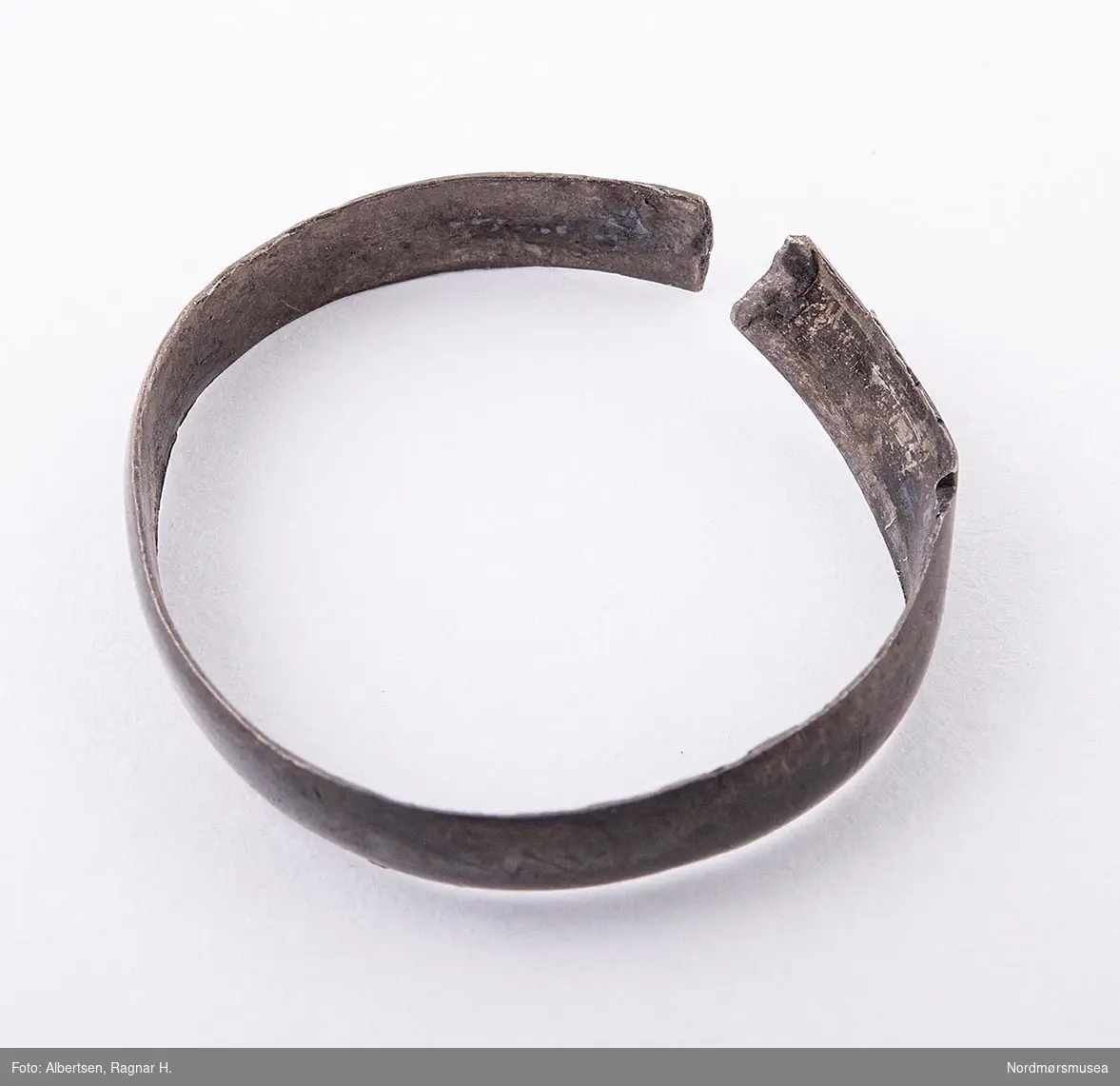 En ring, muligens i sølv, knukket. Ringen ble funnet i en plogdybde på en åker i Sunndal i 1918.